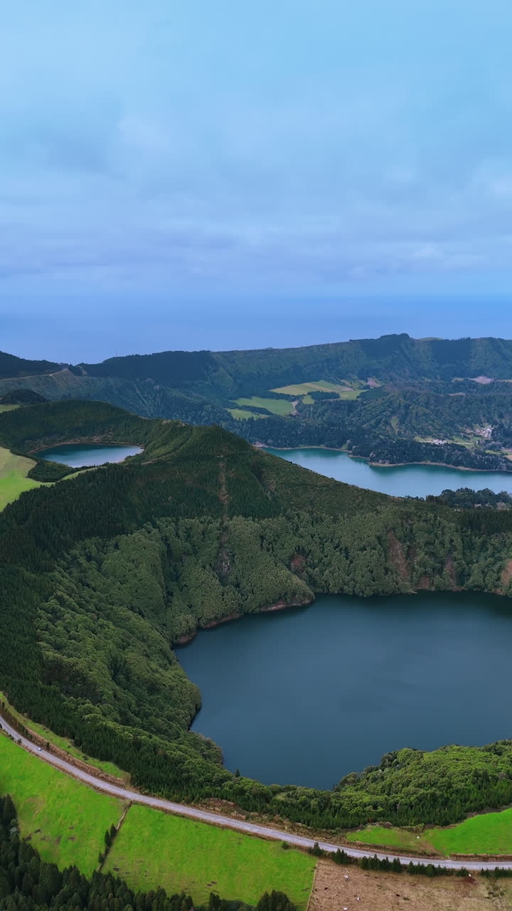 Mountains overgrown with lush vegetation surround the waters of the ocean creating the pools. Stunning Azores from top. Vertical video.