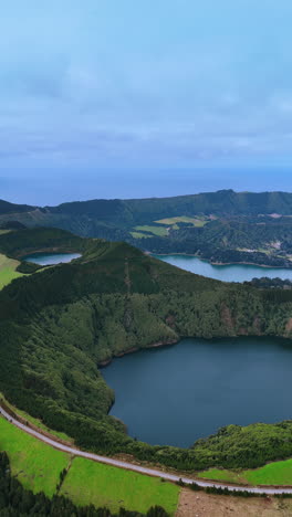 mountains overgrown with lush vegetation surround the waters of the ocean creating the pools. stunning azores from top. vertical video.