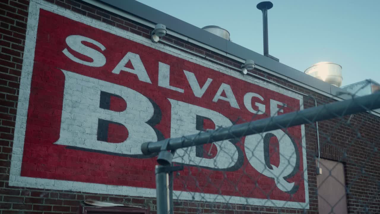 View of colorful SALVAGE BBQ logo on brick designed wall in Portland, Maine, USA.