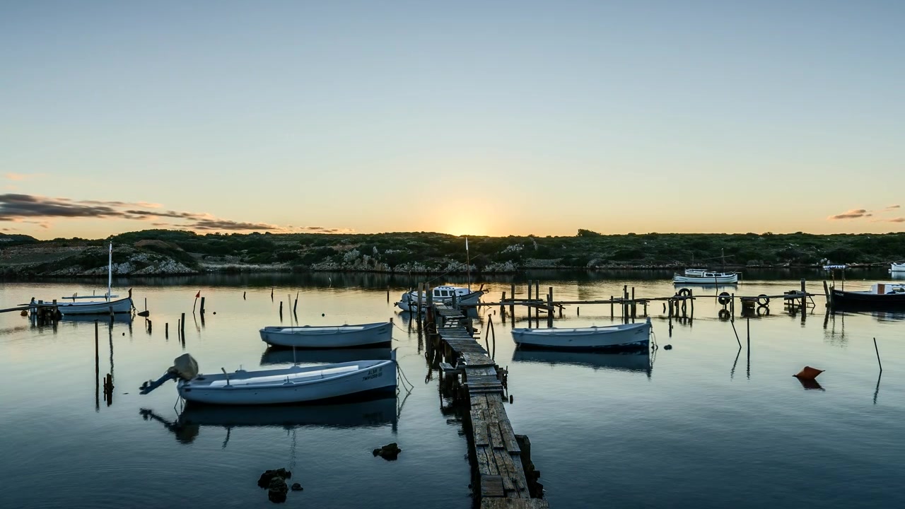 Time lapse evening sunset descending behind Port de Sanitja idyllic mountain harbour landscape
