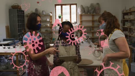 Animación-De-Células-E-íconos-De-Covid-19-Sobre-Mujeres-Que-Usan-Máscaras-Faciales-En-Un-Taller-De-Cerámica