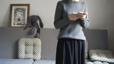 Young-woman-using-mobile-phone-in-cozy-studio