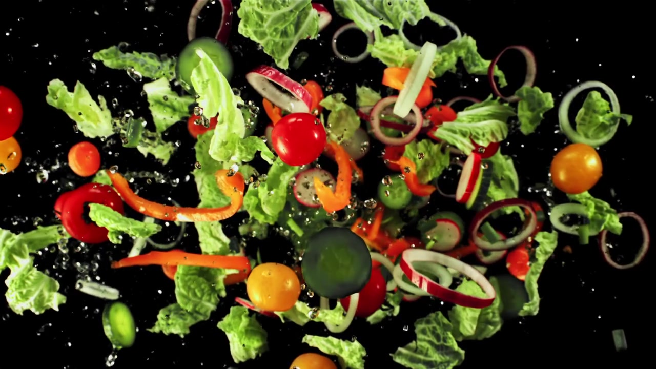 Ingredienti freschi per insalata che cadono e schizzano con acqua al rallentatore