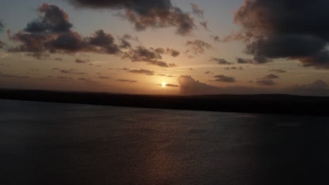 toma aérea derecha de camiones de una impresionante puesta de sol dorada desde el famoso destino turístico alligator beach en un gran río en cabedelo, paraiba, brasil, cerca de la capital costera de joao pessoa