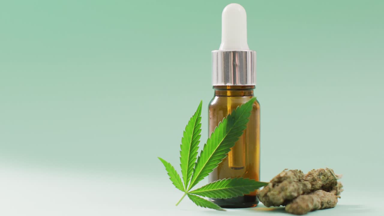 video di foglie e germogli di marijuana e bottiglia di estratto di cbd su sfondo blu