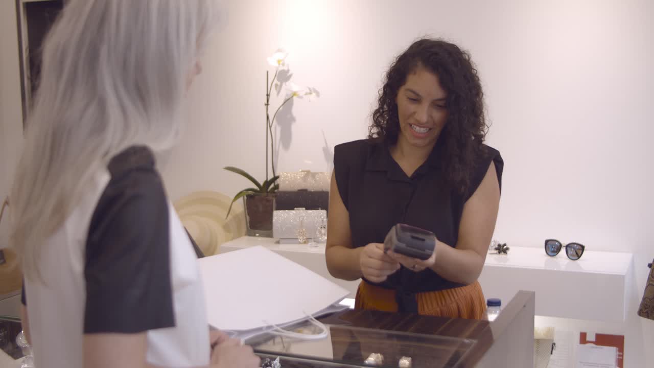 cajero de tienda positivo agradeciendo y dando bolsa de compras al cliente