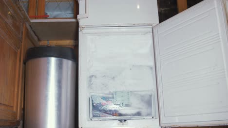 toma frontal estática de un congelador abierto, cubierto de hielo