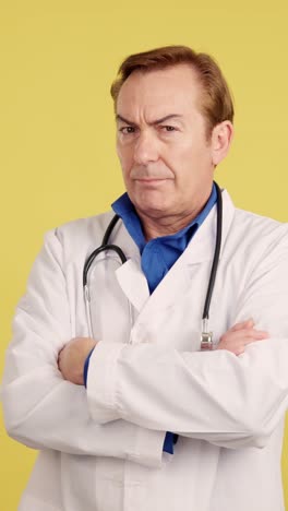 a doctor standing with arms crossed against a yellow background