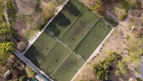 Aerial-circling-shot-showing-six-soccer-fields-with-many-players-playing-football-at-sunset-time-in-Buenos-Aires