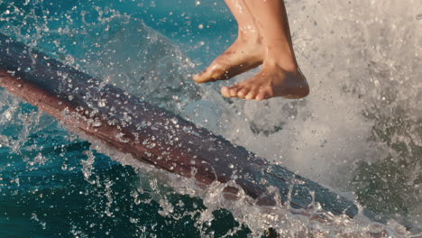 Primer-Plano-De-Las-Piernas-De-Una-Surfista-Femenina-Aterrizando-Un-Gran-Truco-Con-Agua-Salpicando-En-Cámara-Lenta