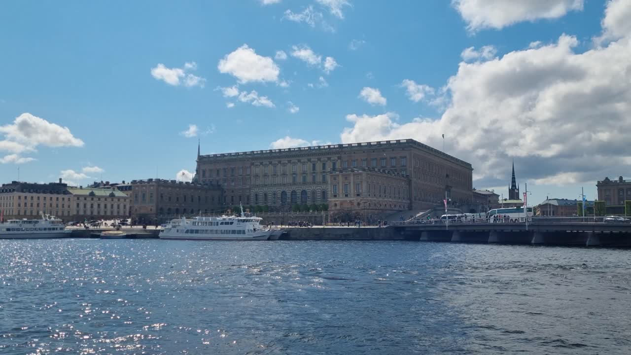 Udsigt over Stockholms slot over Norrström i Stockholm, Sverige, under en klar blå himmel, der fremhæver den historiske havnefront og ikoniske kongelige arkitektur