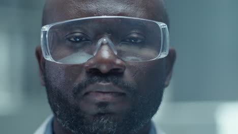 portrait of black male chemist wearing protective glasses in laboratory