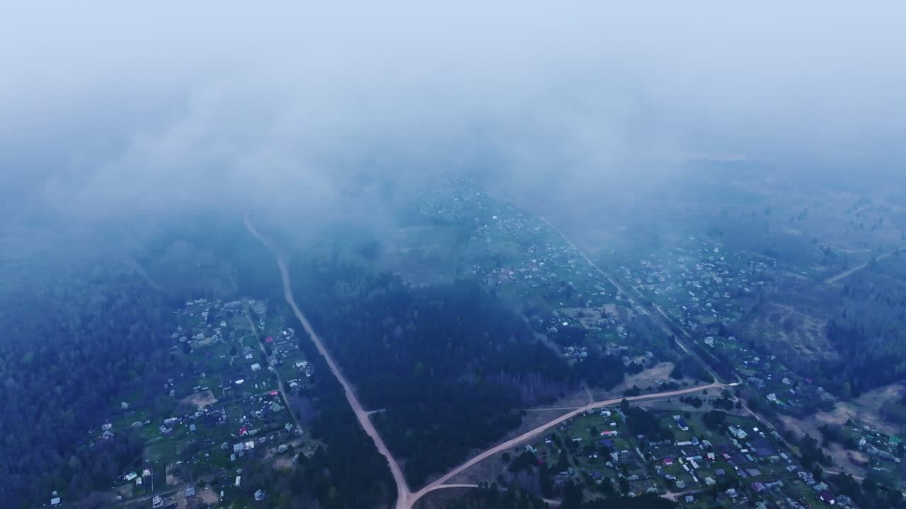 Soft drifting clouds cover distant forest roads in calm blue morning air