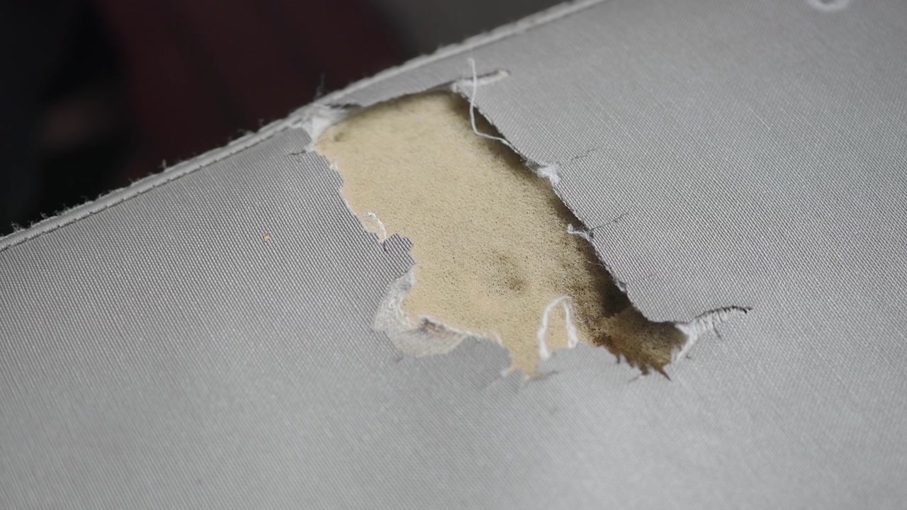Close-up of Torn Gray Fabric Revealing Yellow Foam
