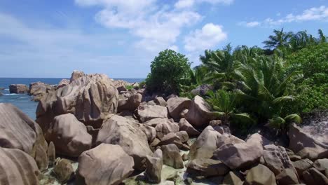 Drone-shot-of-beach-with-granite-rocks,-white-sand,-and-blue-sky-in-tropical-Paradise,-La-Digue,-Seychelles