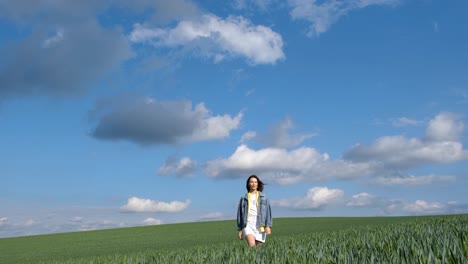 beautiful girl with long hair dressed in a denim jacket walks alone on a green field beautiful girl with long hair dressed in a denim jacket walks alone on a green field happy free young girl in green wheat