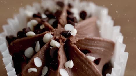 animation of snow falling over cupcake on wooden background