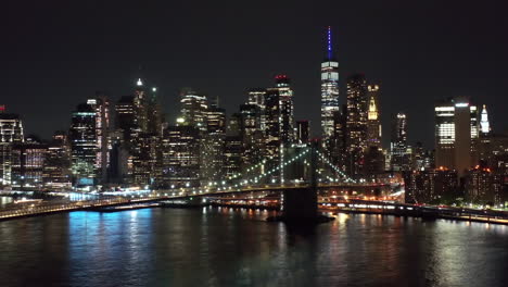 Hermosas-Imágenes-Nocturnas-De-Drones-Del-Horizonte-De-La-Ciudad-De-Nueva-York-Que-Muestran-La-Torre-De-La-Libertad,-El-Río-Hudson,-El-Bajo-Manhattan,-El-Distrito-Financiero-Y-El-Barrio-Chino,-Filmadas-Desde-Brooklyn