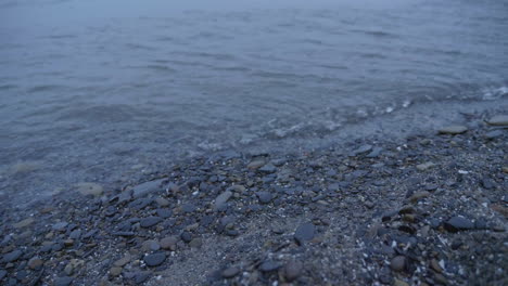 cool colored waves rolling onto a gravel shore