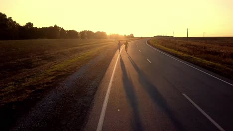 two people running on a country road at sunset