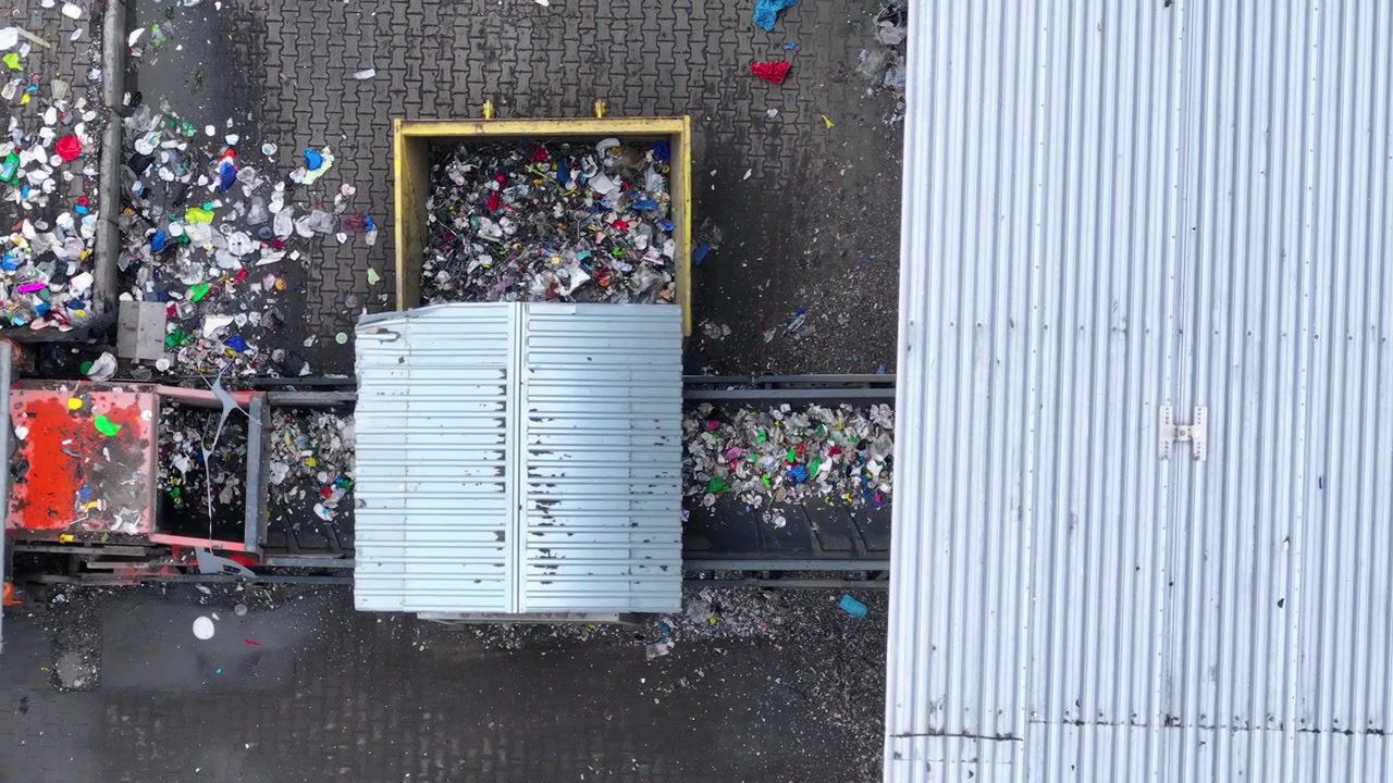 Plastic waste is transported and sorted at a recycling facility. Recyclable materials are processed for reuse. The facility focuses on sustainable waste management practices.
