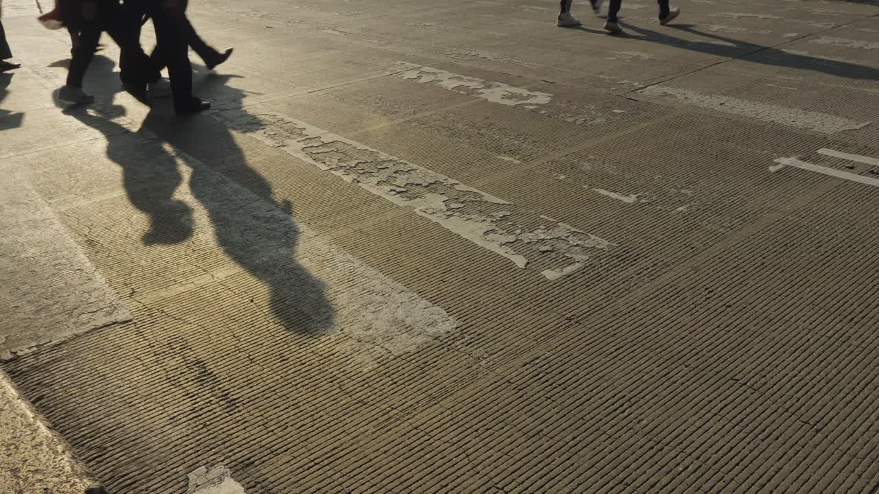 Wide and cinematic angle of Pedestrian shadows crossing a street during golden hour sunset