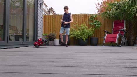 young boy at home outdoors in the garden playing with his rc car, truck, 4 x 4