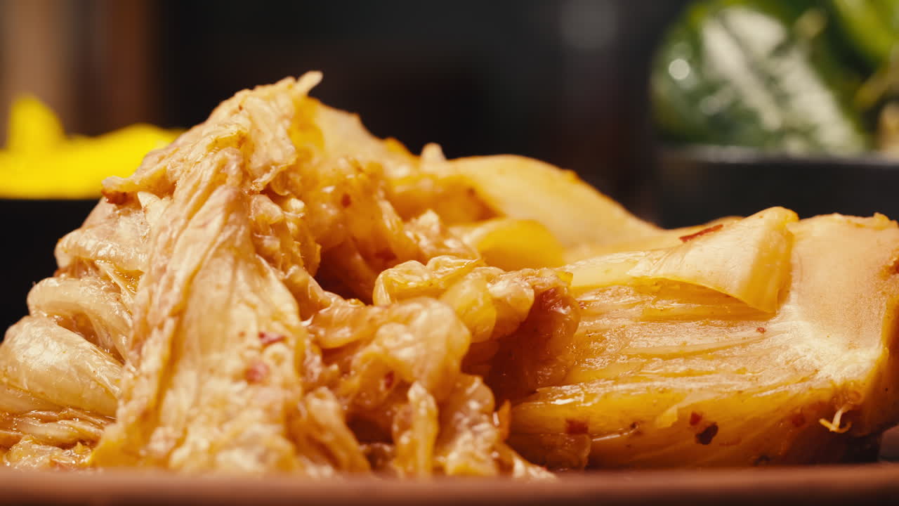 Taking a little bit of fermented spicy cabbage kimchi by fork close-up. Preservation of vegetables in glass jars. Fermentation preserved kimchi cabbage with spices macro. Asian cuisine.