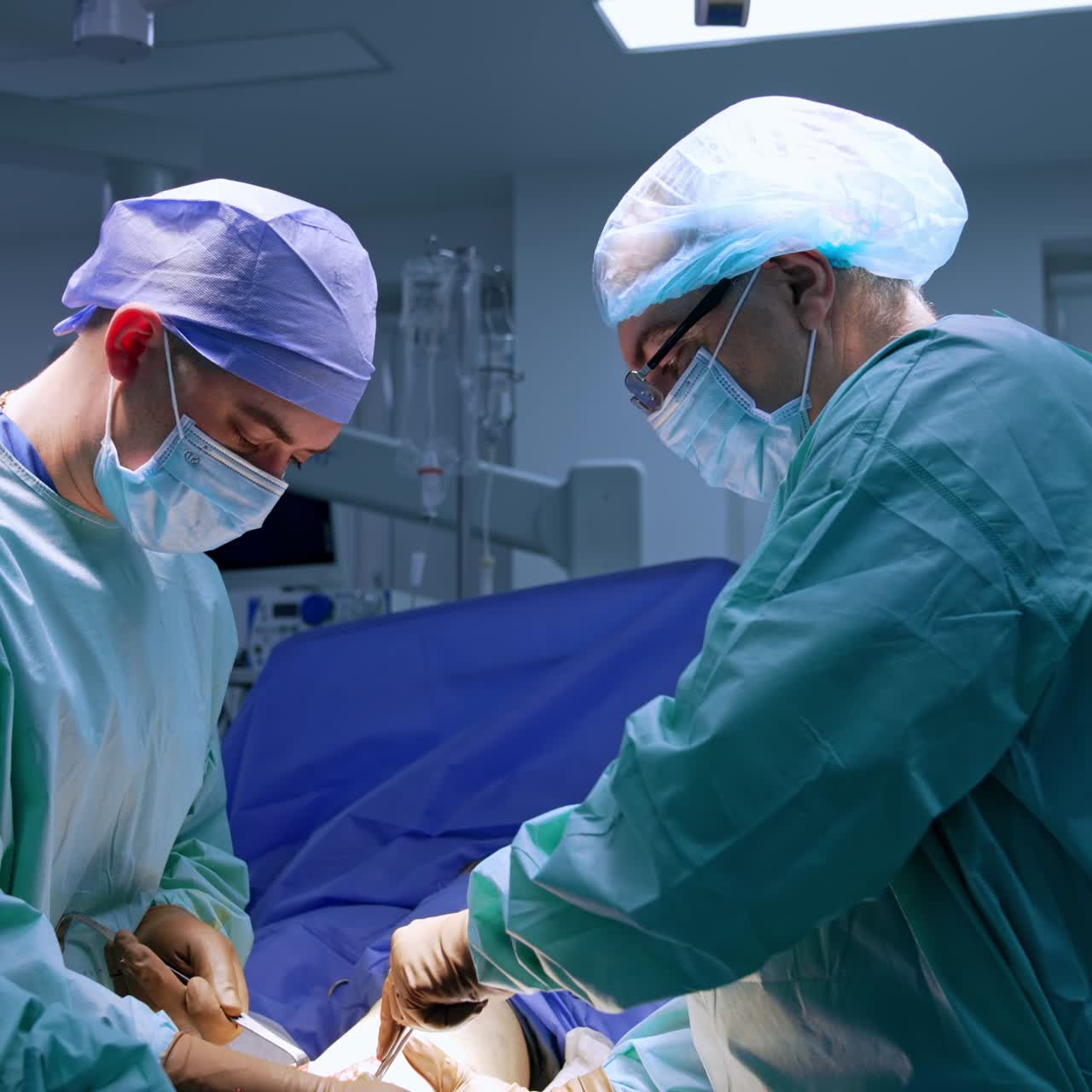 Group of medics working in the modern surgery theatre. Surgeons use metal tool performing operation on foot