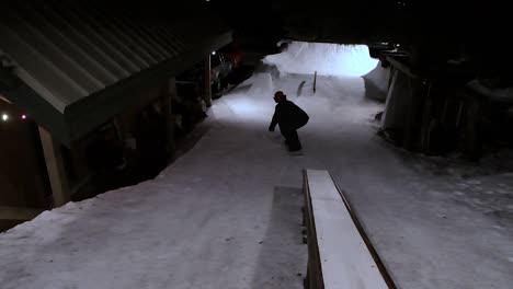 male snowboarder on rail in a park built in his backyard at night