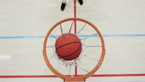 high angle of african american male basketball player shooting ball at hoop on court, slow motion