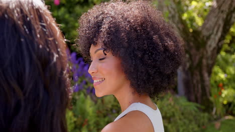 smiling woman with curly hair enjoying outdoor conversation in garden setting