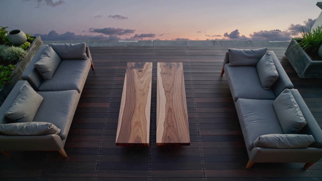 Deepening sunset sky casting soft shadows on rooftop deck, revealing grey sofas and wooden table