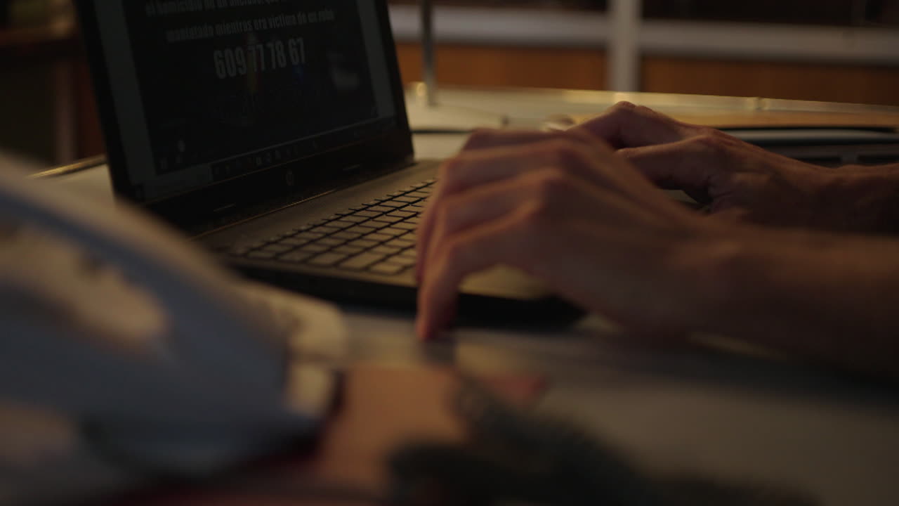 Person working on a laptop and using a phone.