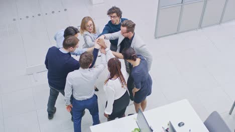 trabajadores de oficina haciendo ejercicio de team building apilando las manos juntos en el espíritu unificador de la creatividad y la causa común. ocho personas exitosas aplaudiendo juntos. fotografía de ángulo alto en una oficina moderna