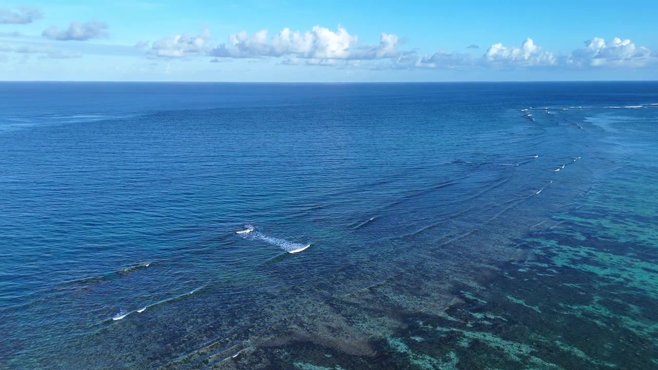 Onde calme in un oceano tropicale blu esotico si infrangono sul bordo della barriera corallina, vista aerea dall'alto.