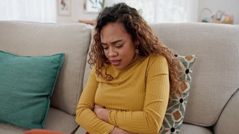 woman suffering from stomach pain sitting on a couch