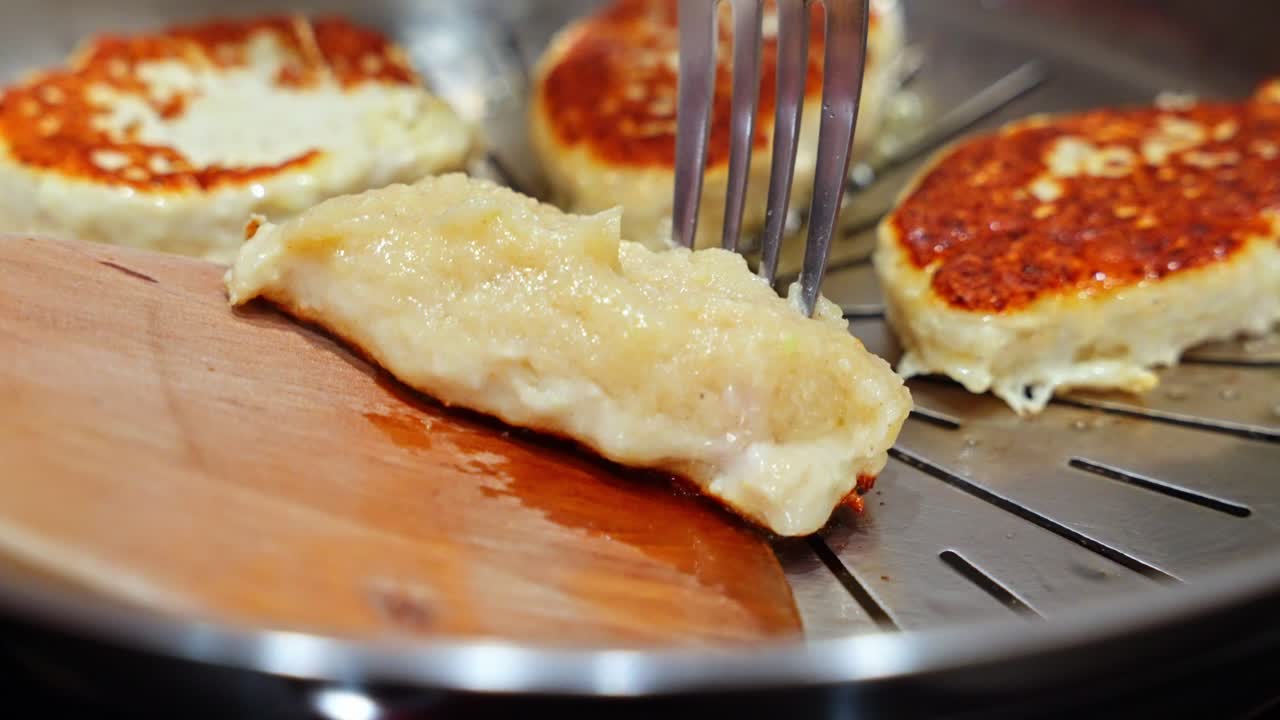 Spatula membalik potongan daging ayam yang memperlihatkan kulit kecoklatan saat terus digoreng dalam minyak panas