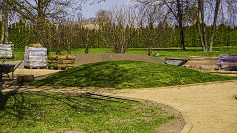 static shot of workers covering hillock with green artificial grass carpet in timelapse on park floor on a summer day