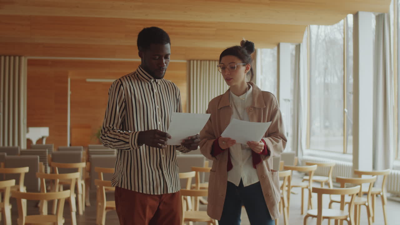 Young Man and Woman Discussing Papers in Auditorium