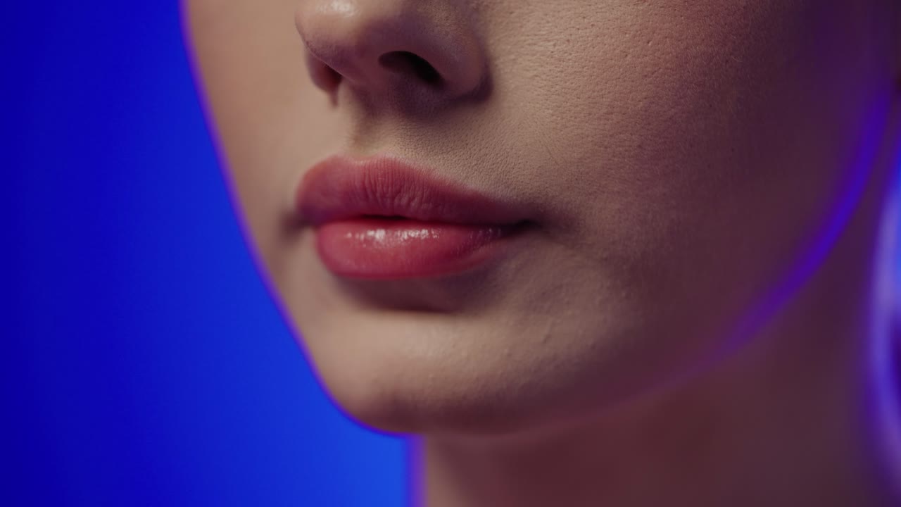 primer plano extremo de una mujer joven con hermosos labios rojos tomando una cápsula para su salud con ingredientes saludables frente al fondo azul en cámara lenta