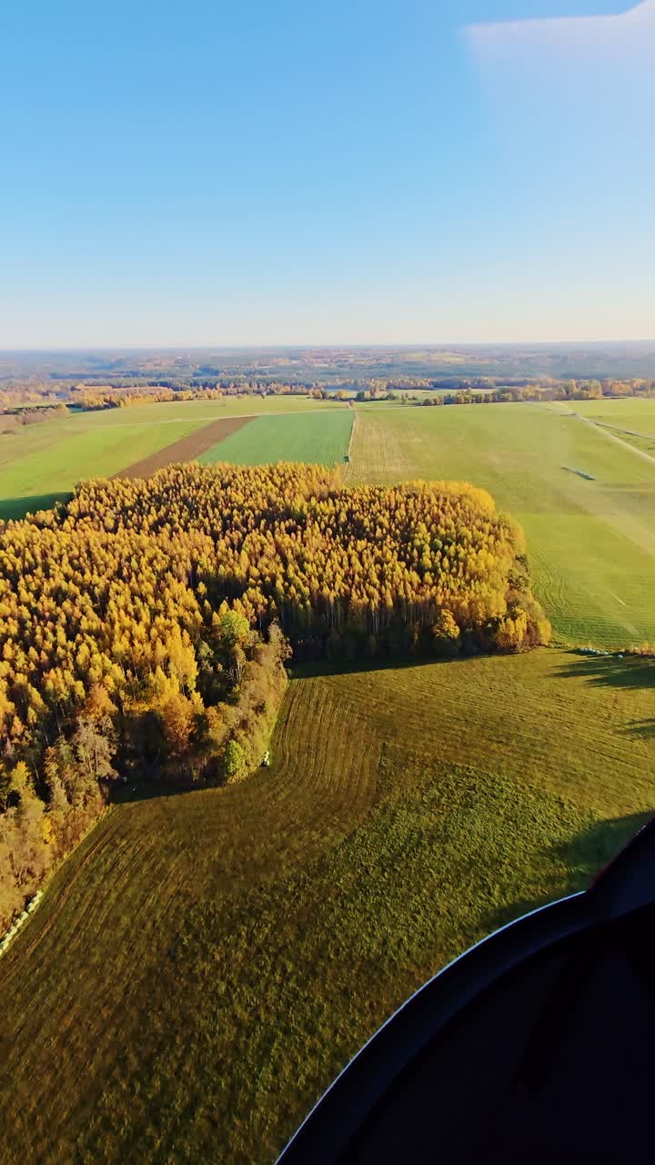 Helicopter cockpit view reveals fall-colored countryside, clear flowing water
