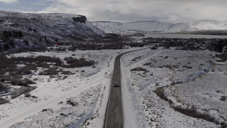 Descending aerial movement over the snowy road stretching through beautiful cold mountain valley towards Caviahue-Copahue, Nequén, Argentina