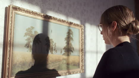 woman observing a painting in a room