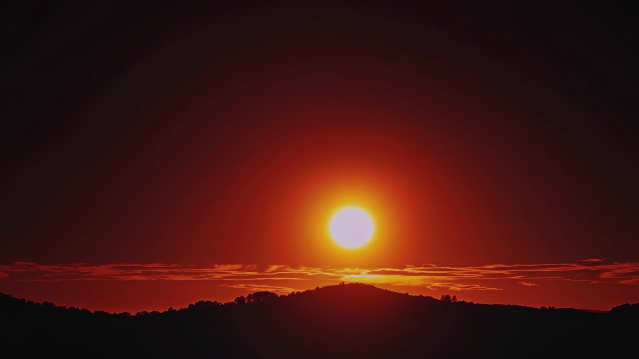 En betagende solnedgangsvideo viser solen gå ned over bakker, optaget fra en lav vinkel.