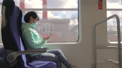 woman wearing a protective medical face mask rides on a train during the covid 19 quarantine.