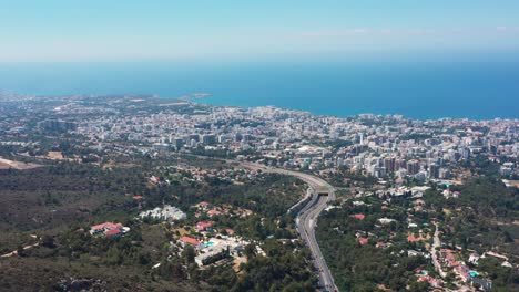 Volando-Por-Encima-De-Una-Autopista-Con-Vistas-A-La-Ciudad-En-Expansión-Hacia-El-Mediterráneo