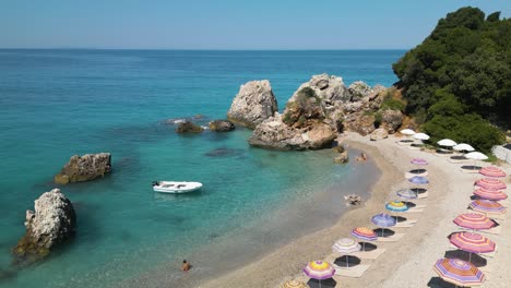 people play in water in small protected cove or bay with beach chairs and colorful umbrellas on shore