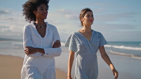 two girls going beach in summer morning. relaxed lgbt couple talking ocean shore