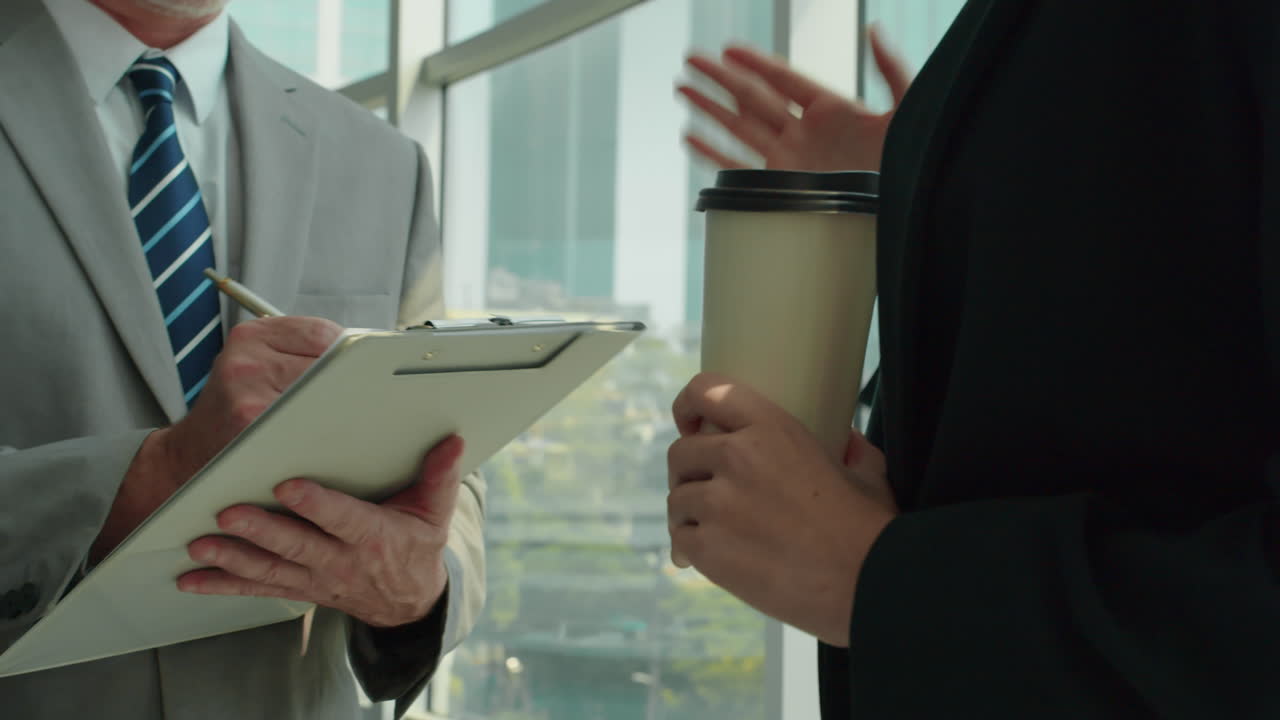 Businessman Making Notes when Talking to Businesswoman